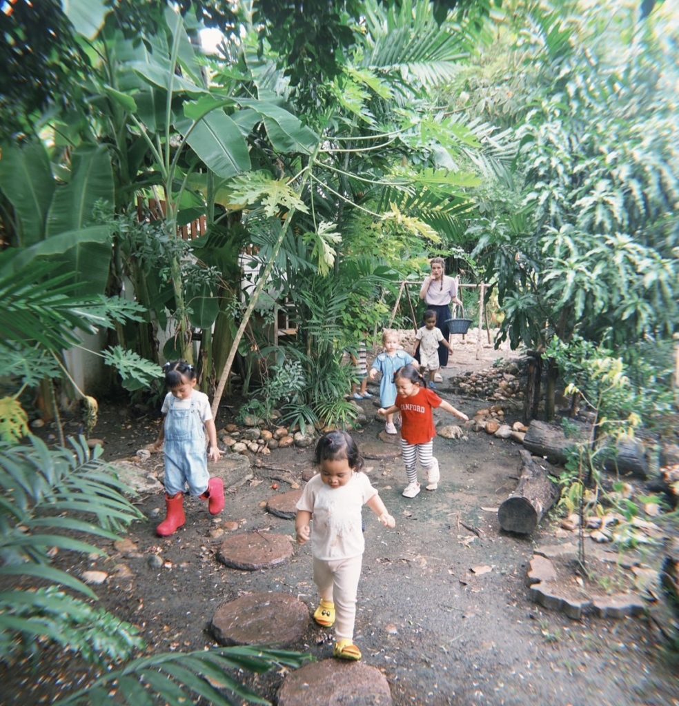 A group of kids on a scavenger hunt during forest play at Firefly Forest School in Bangkok.

