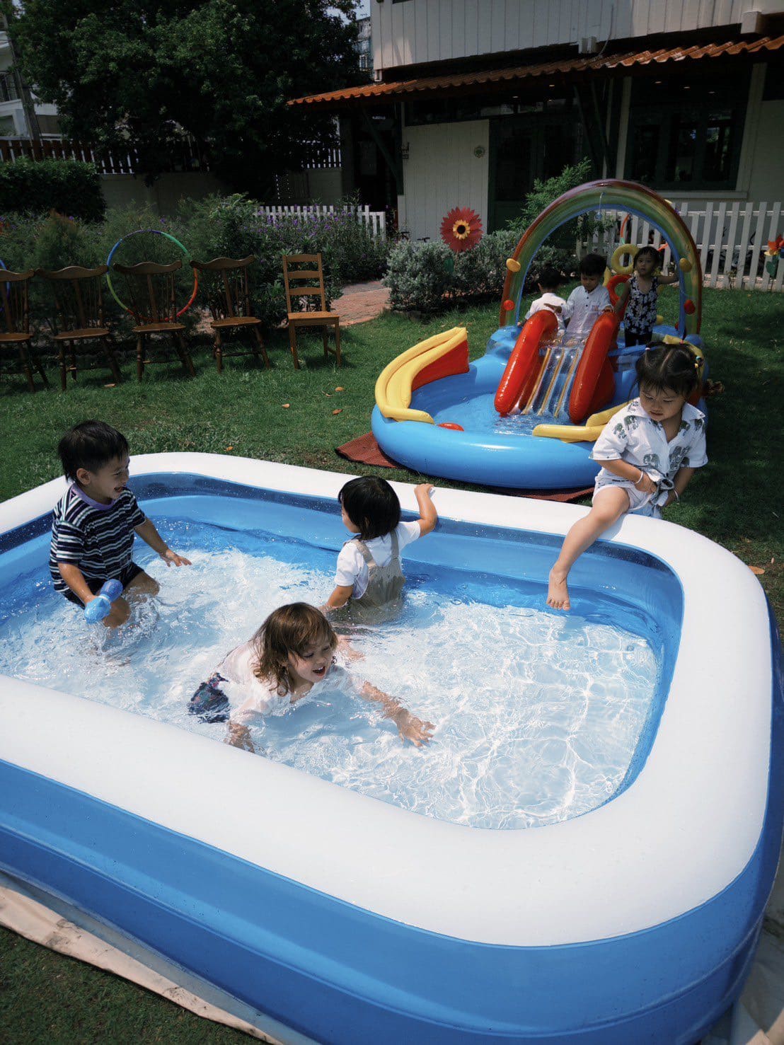 Children splashing in a pool during a swimming lesson at Firefly Forest School in Bangkok.