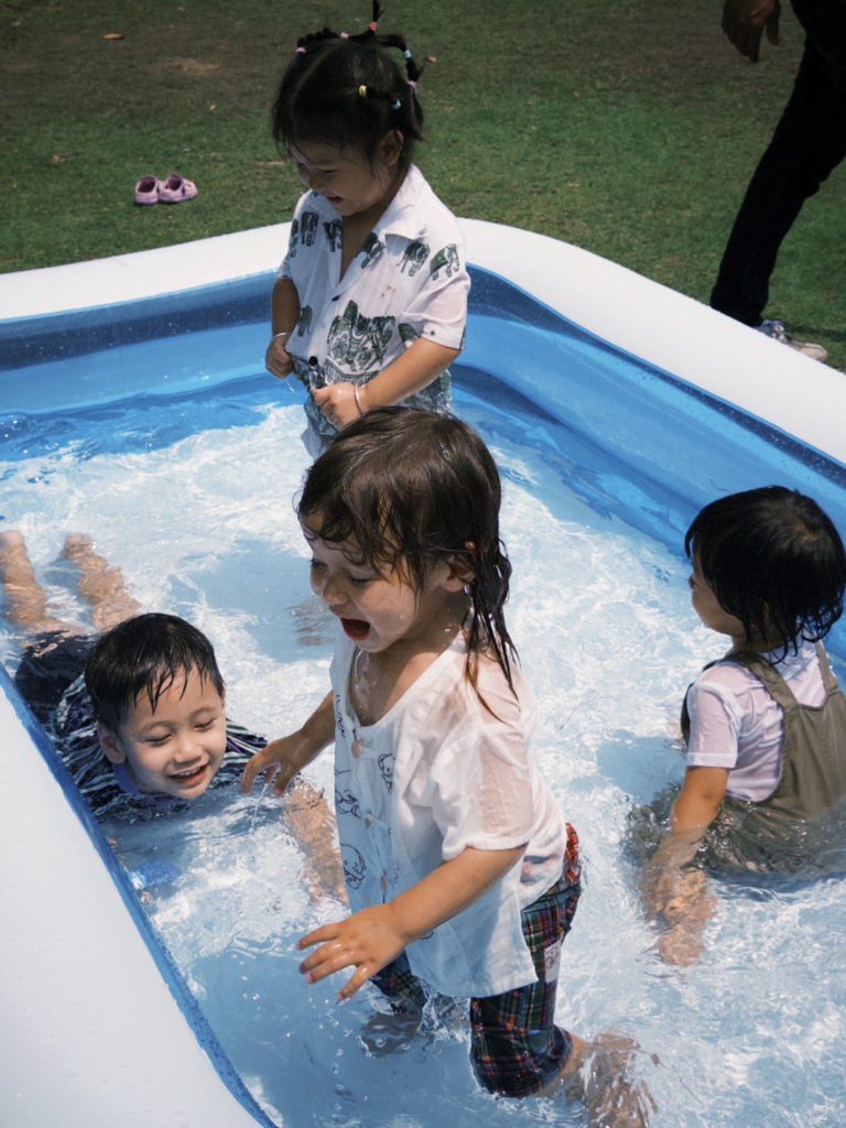 Children splashing in a pool during a swimming lesson at Firefly Forest School in Bangkok.

