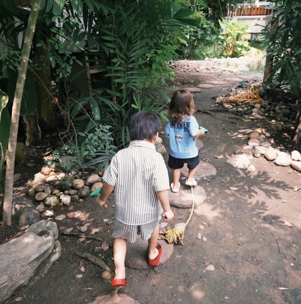  "Toddlers exploring the Secret Garden at Firefly Forest School during a nature-based preschool activity in Bangkok."

