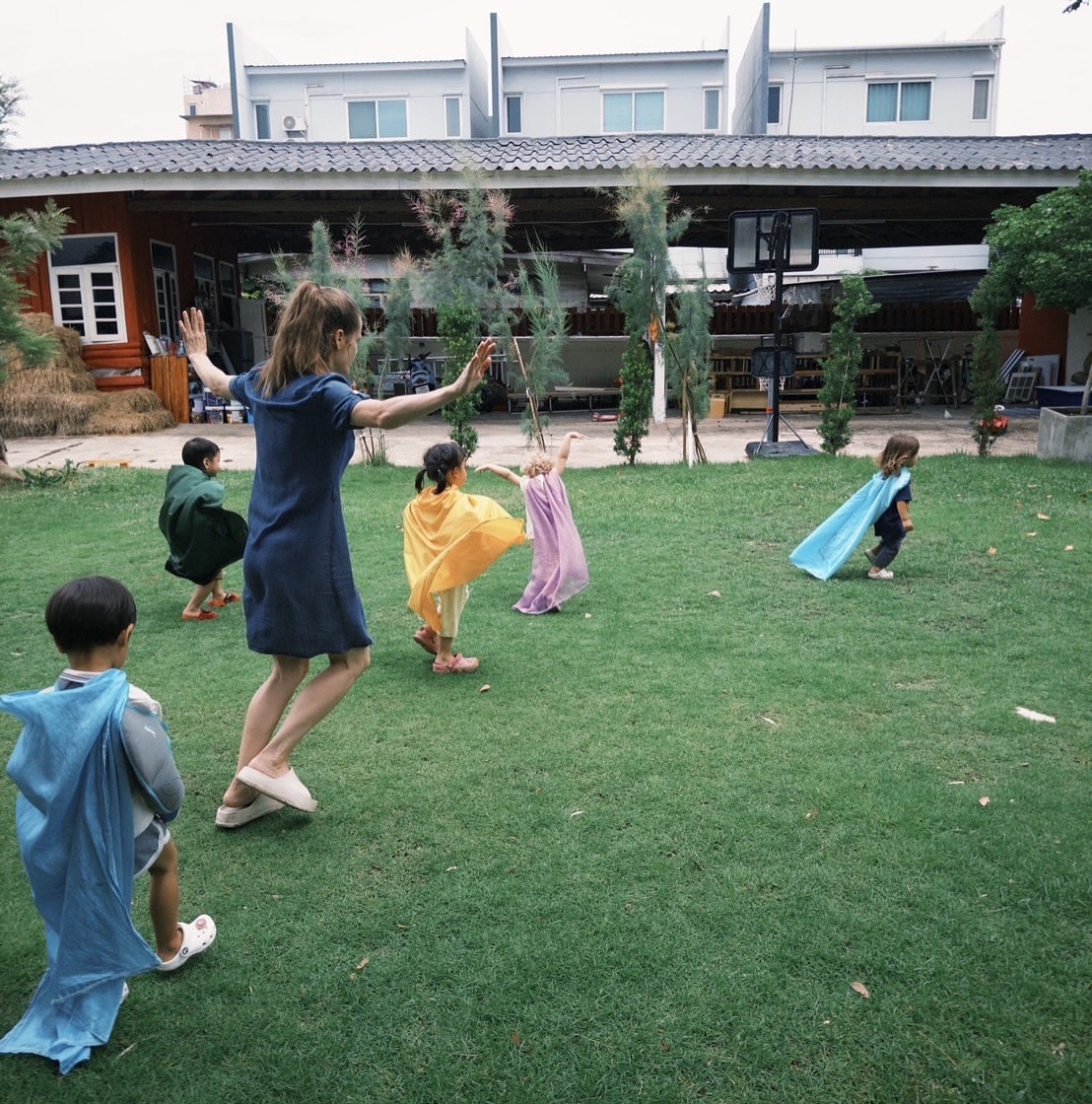 A group of kids creating a nature mural with leaves at Firefly Forest School’s kindergarten in Bangkok.