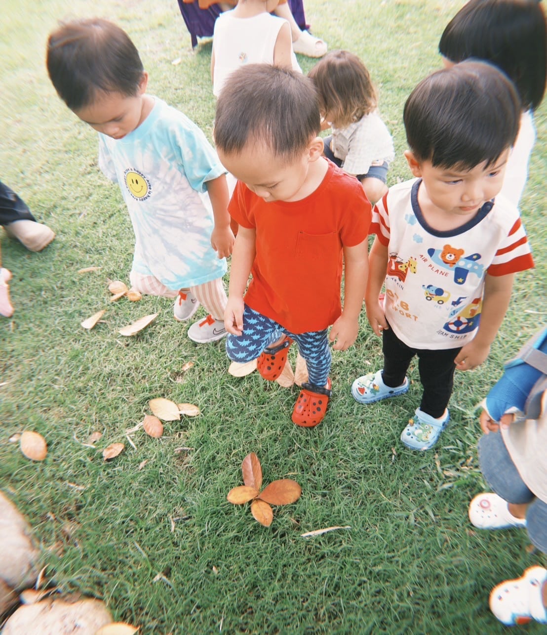 "Toddlers splashing in puddles during a nature camp at Firefly Forest School in Bangkok."