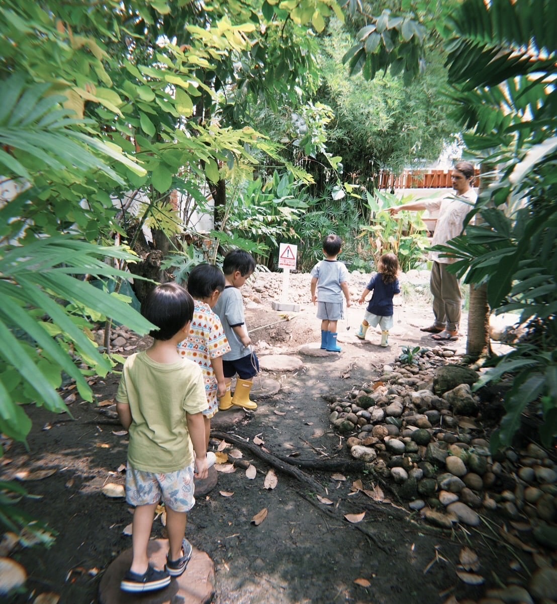 A group of kids on a scavenger hunt during forest play at Firefly Forest School in Bangkok.
