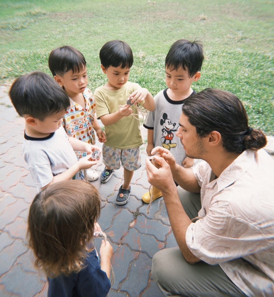 "Toddlers splashing in puddles during a nature camp at Firefly Forest School in Bangkok."


