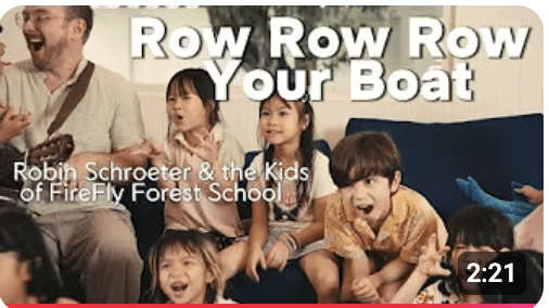 FireFly Forest School children singing and pretending to row boats during Row Row Row Your Boat song